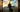 Man with large luggage in front of a sunset.